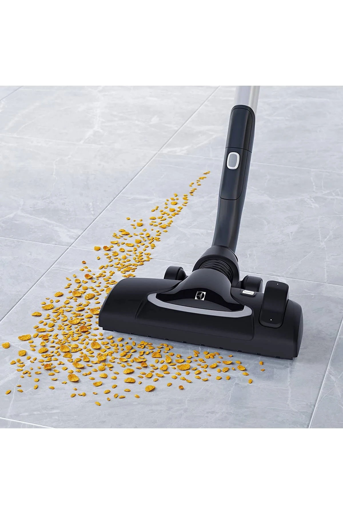 Czarna głowica odkurzacza na szarej podłodze z płytek, czyszcząca żółte zanieczyszczenia.