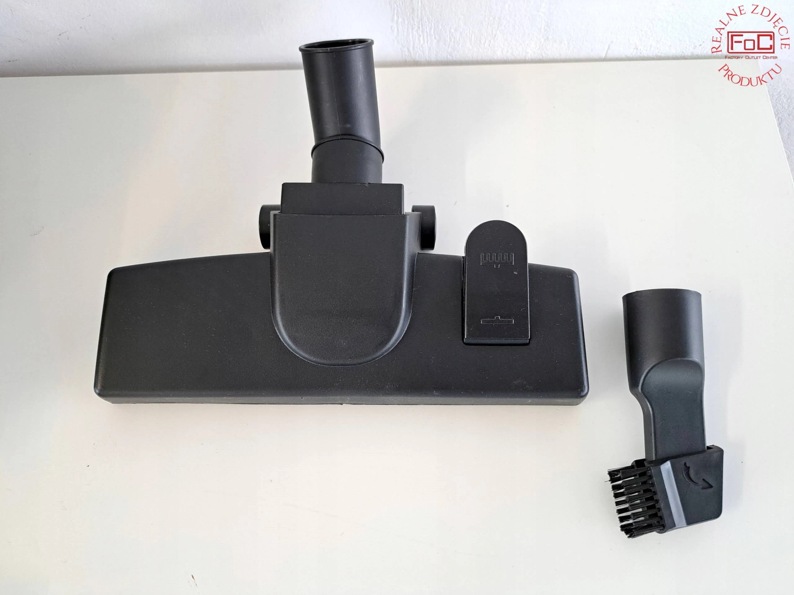 Głowica odkurzacza i akcesoria na białej powierzchni, z logo po lewej stronie u góry.