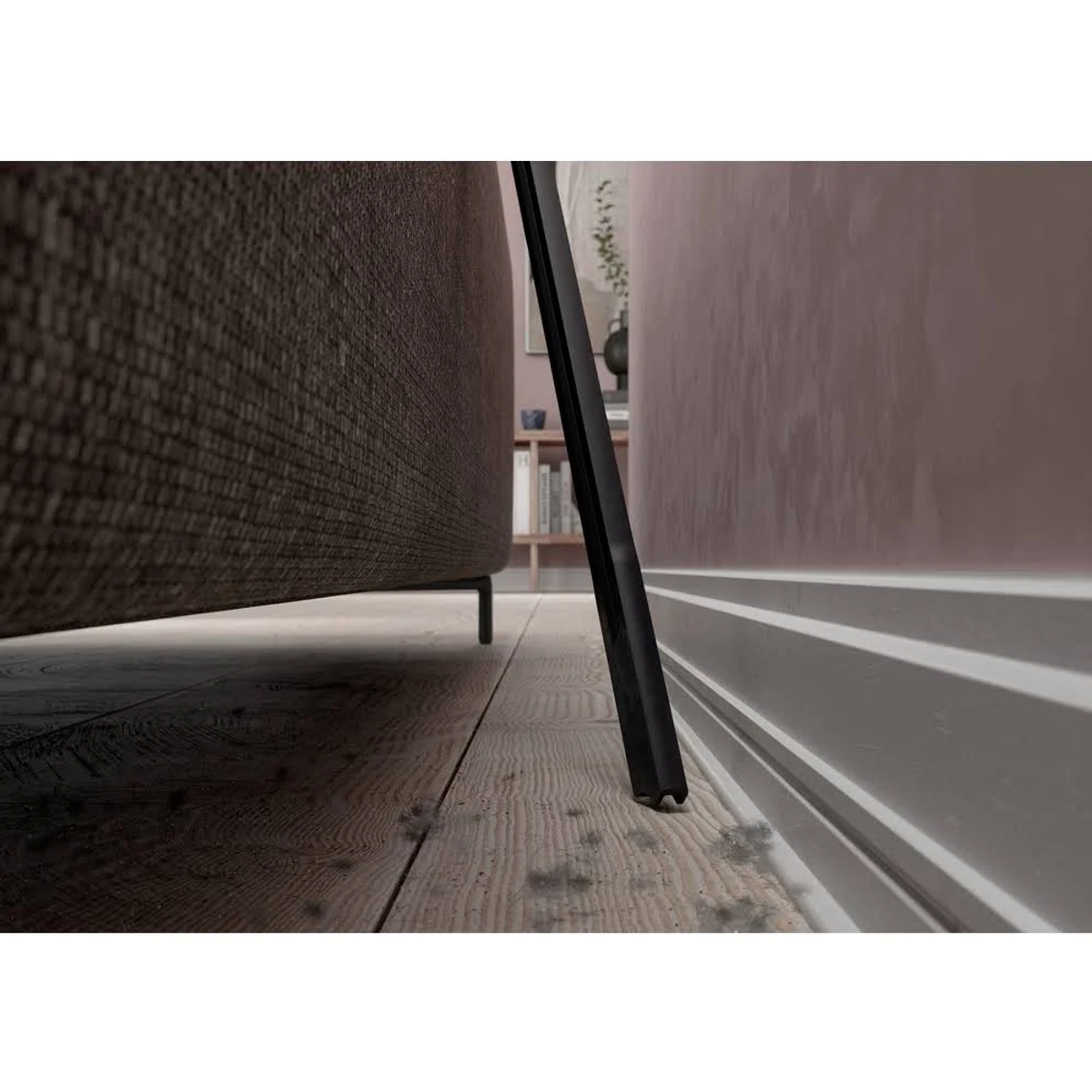 Ujęcie z niskiego kąta, drewniana podłoga, sofa i czarny obiekt na tle ściany.