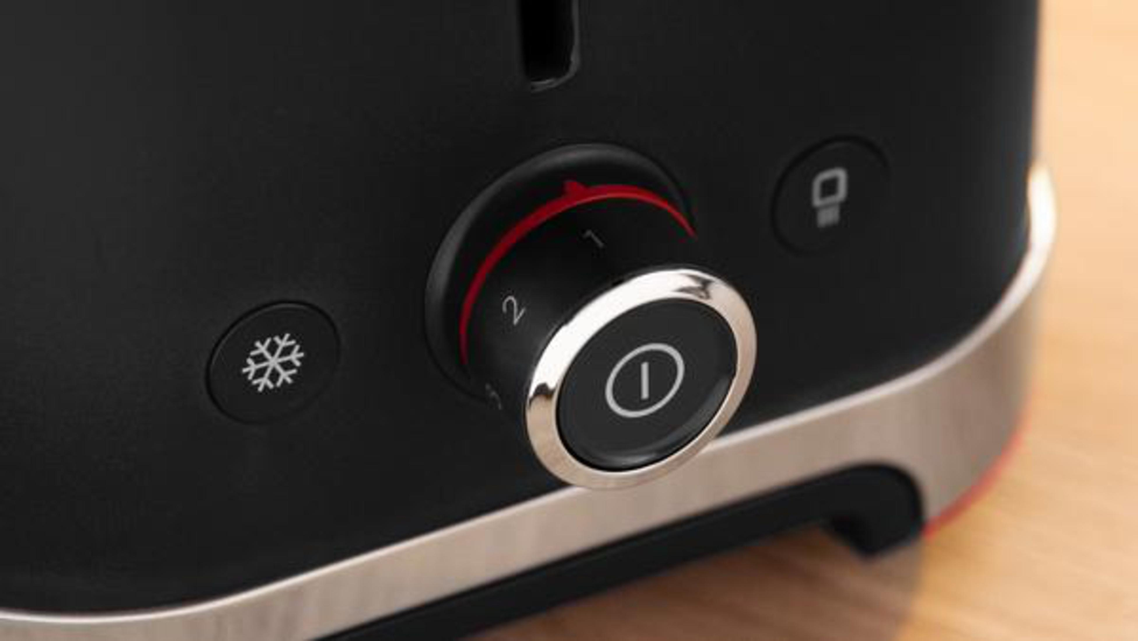 Zbliżenie czarnego i srebrnego tostera. Pokrętło jest ustawione na 2, z przyciskiem zasilania.