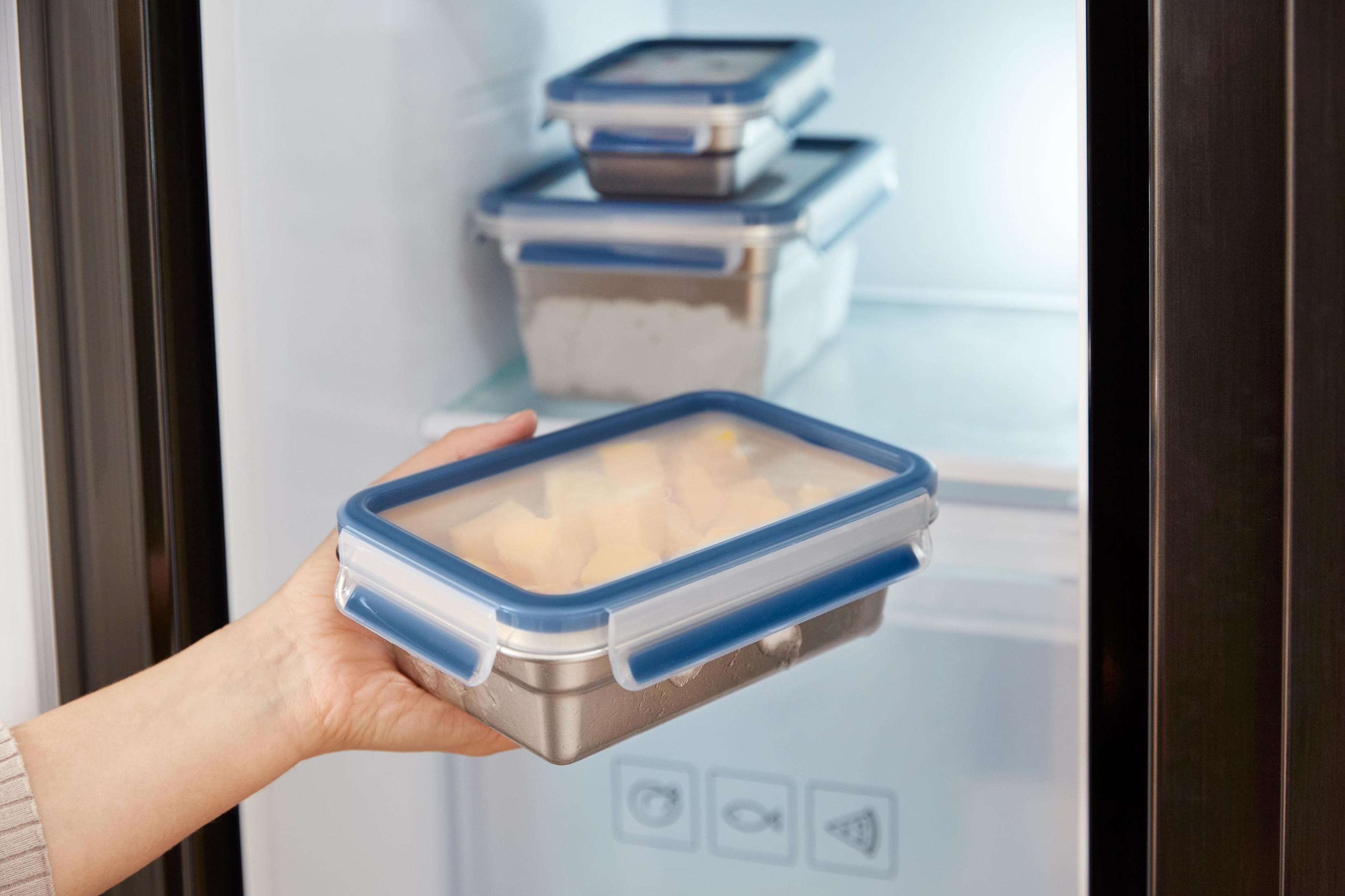 Hand nimmt Lebensmittelbehälter aus dem Kühlschrank. Andere Behälter sichtbar.