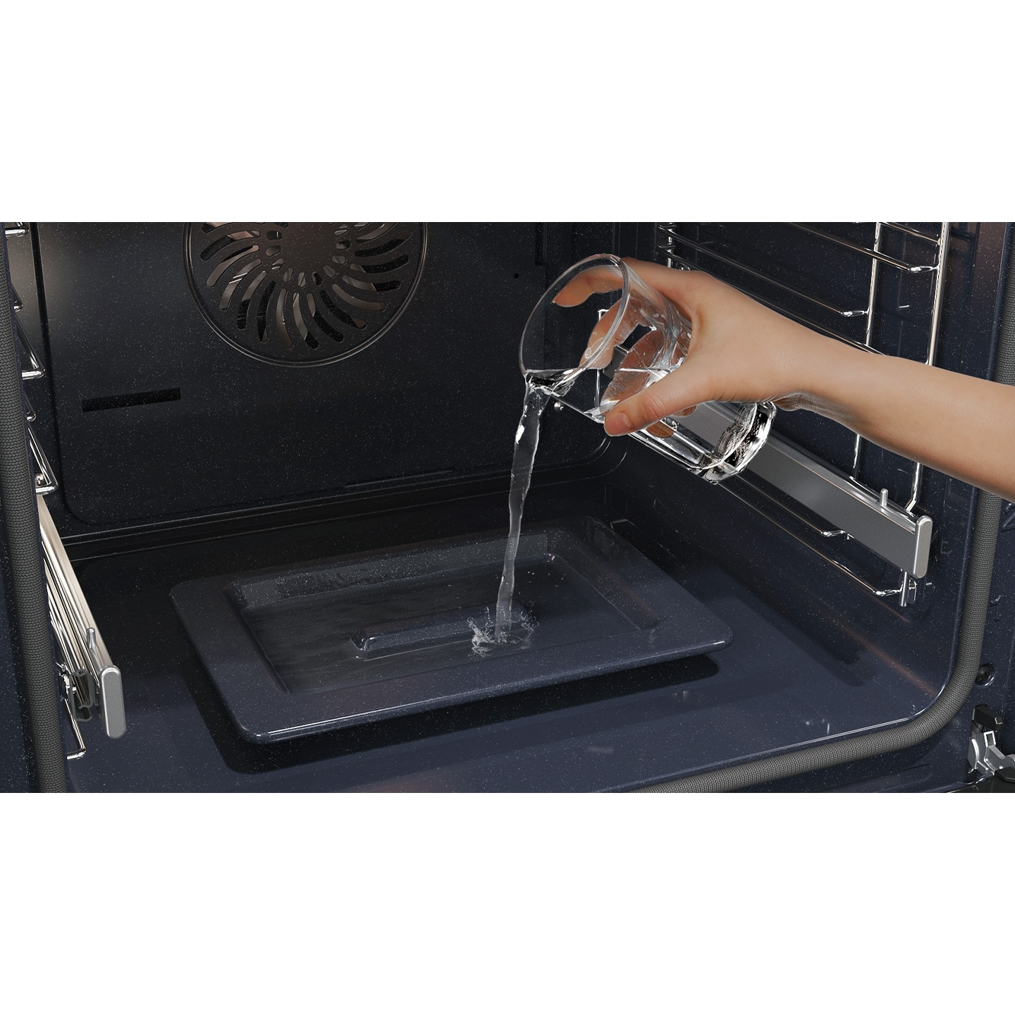 Una persona versa acqua da un bicchiere in una teglia nera all'interno di un forno.