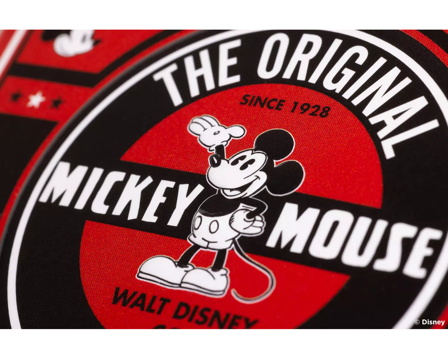 Gros plan de Mickey Mouse sur un fond rouge et noir. Le logo dit 'The Original Mickey Mouse'.