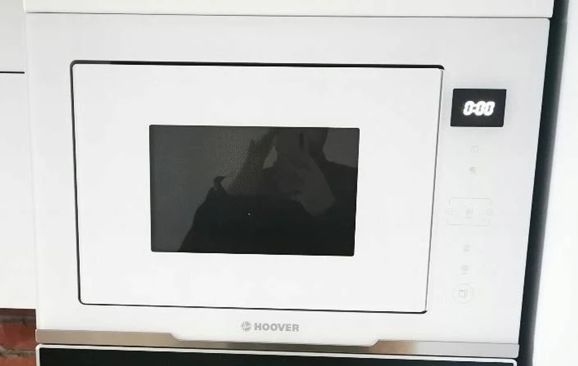 Biała kuchenka mikrofalowa z cyfrowym wyświetlaczem pokazującym 0:00.