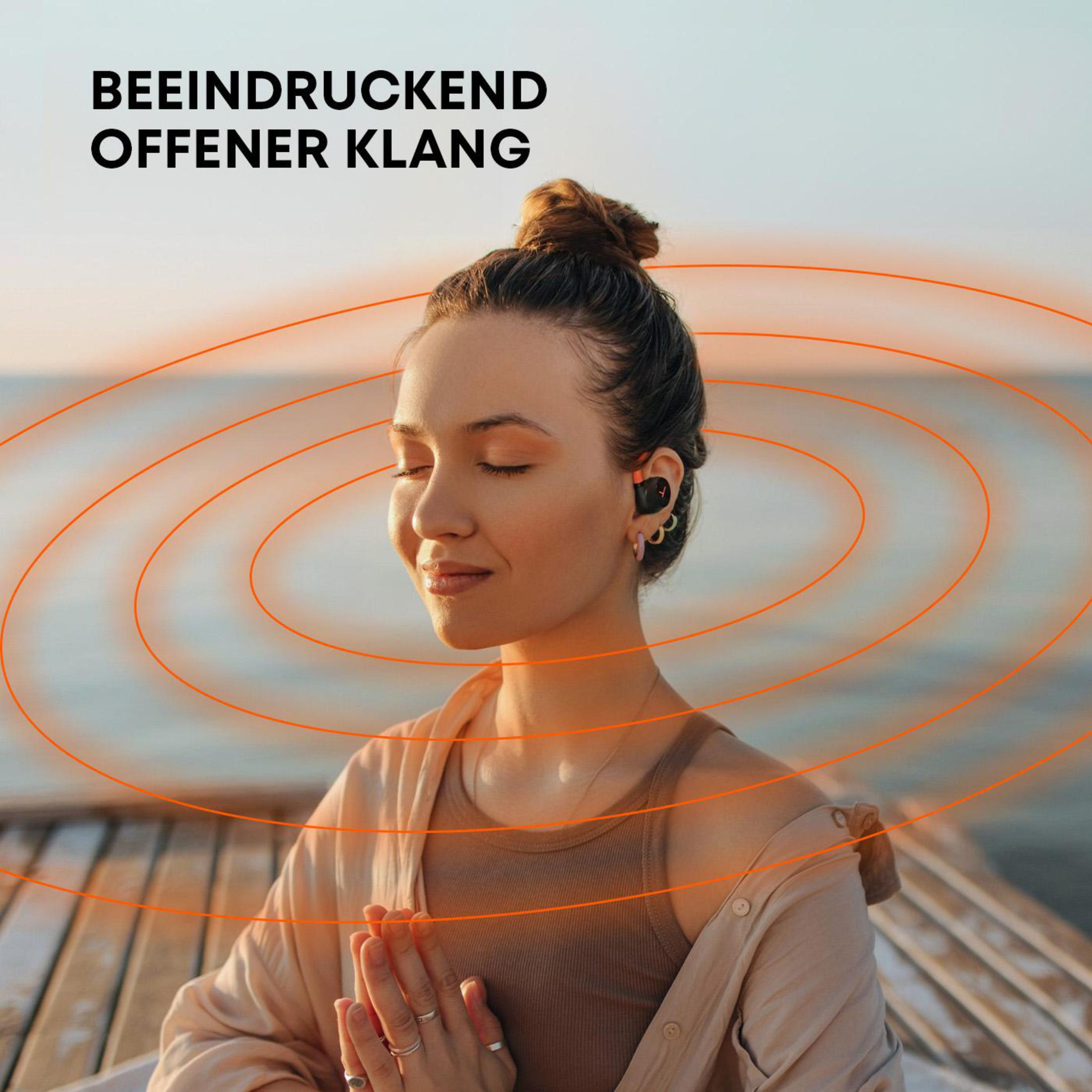 Kobieta ze słuchawkami, oczy zamknięte. Pomarańczowe okręgi i rozmyte tło.