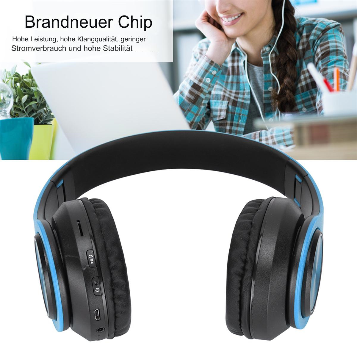 Schwarze und blaue Kopfhörer auf einem Schreibtisch. Person im Hintergrund mit Kopfhörern sichtbar.