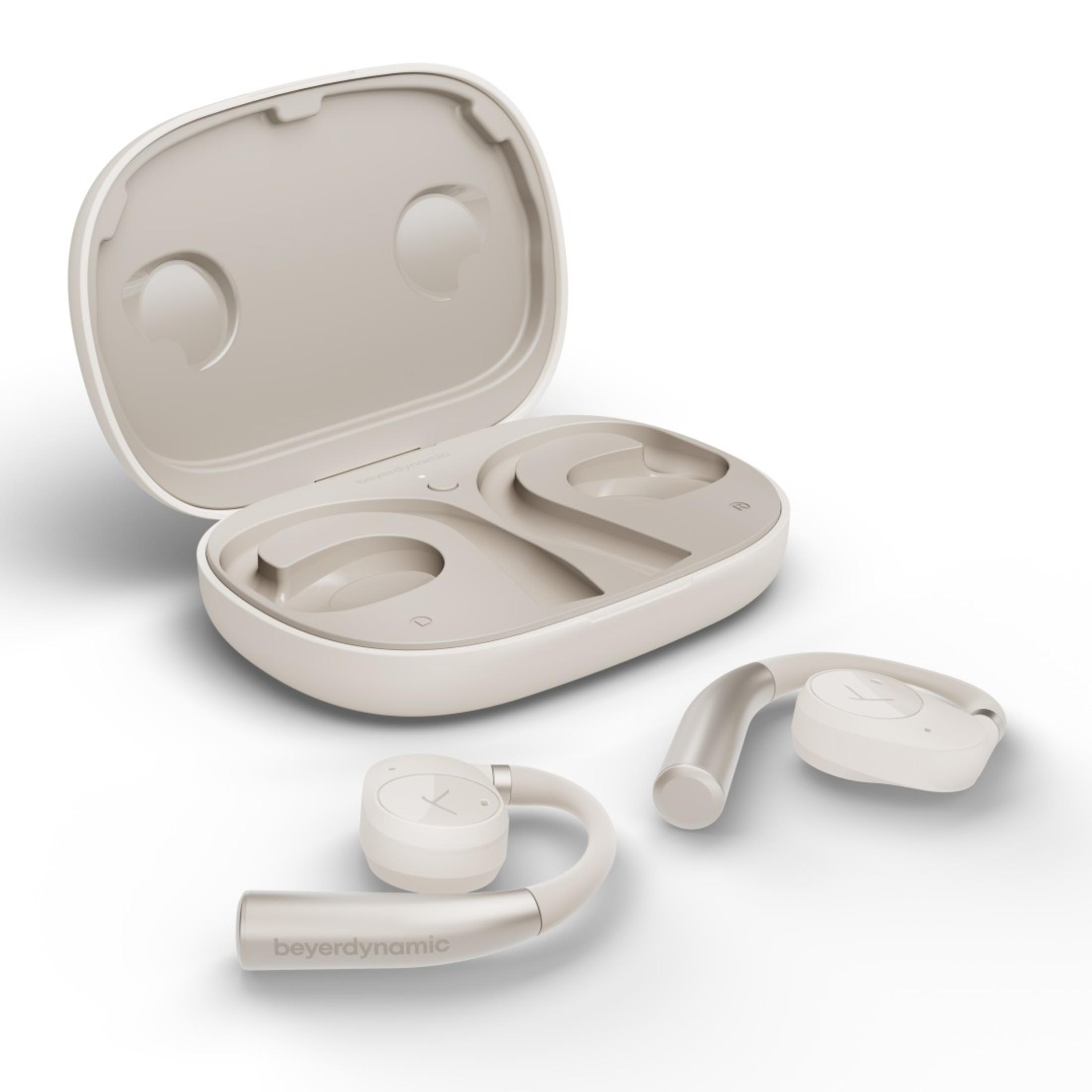 Białe i srebrne słuchawki douszne, z etui ładującym, na białej powierzchni.