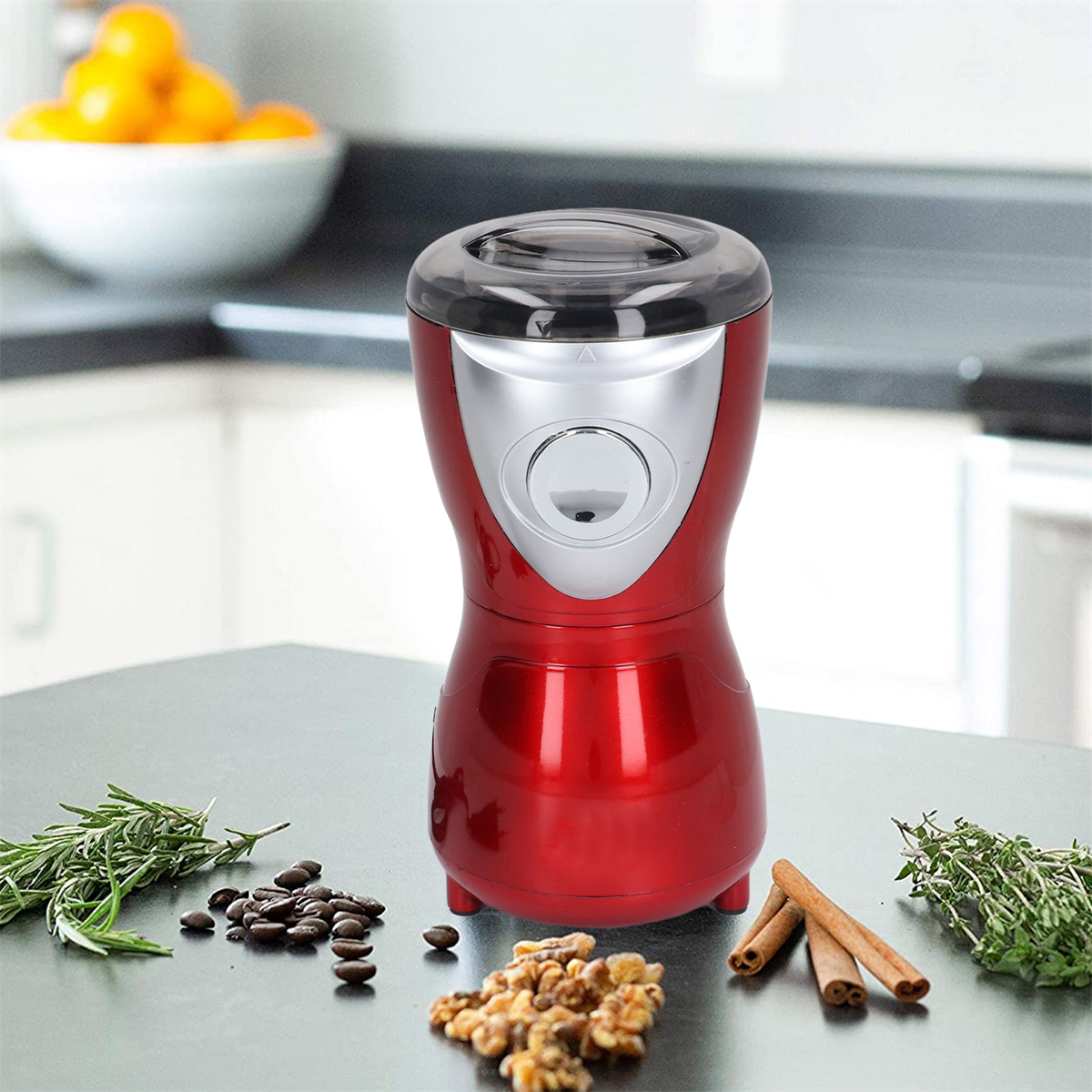 Rote Kaffeemühle, Bohnen, Nüsse, Zimt und Kräuter auf einer Küchenarbeitsplatte.