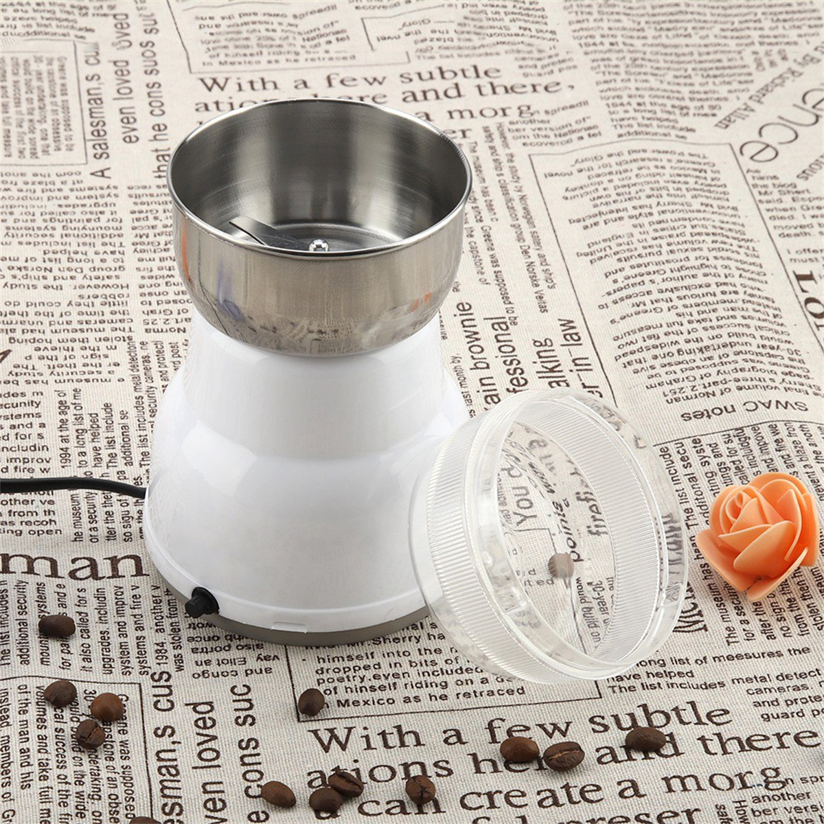 Ein Grinder mit Edelstahlkomponenten. Kaffeebohnen und eine Rose sind darum verstreut.