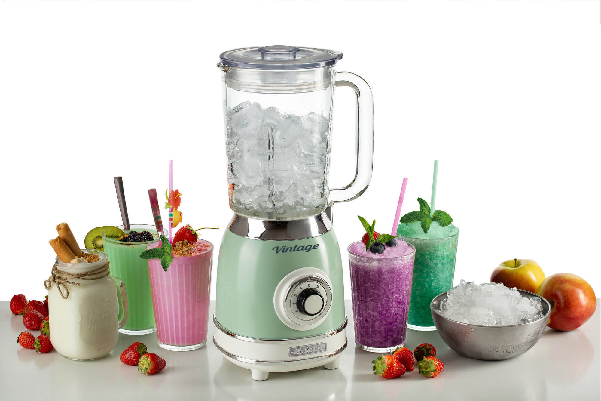 Blender met ijs. Dranken met rietjes, fruit en een kom met ijs ernaast.