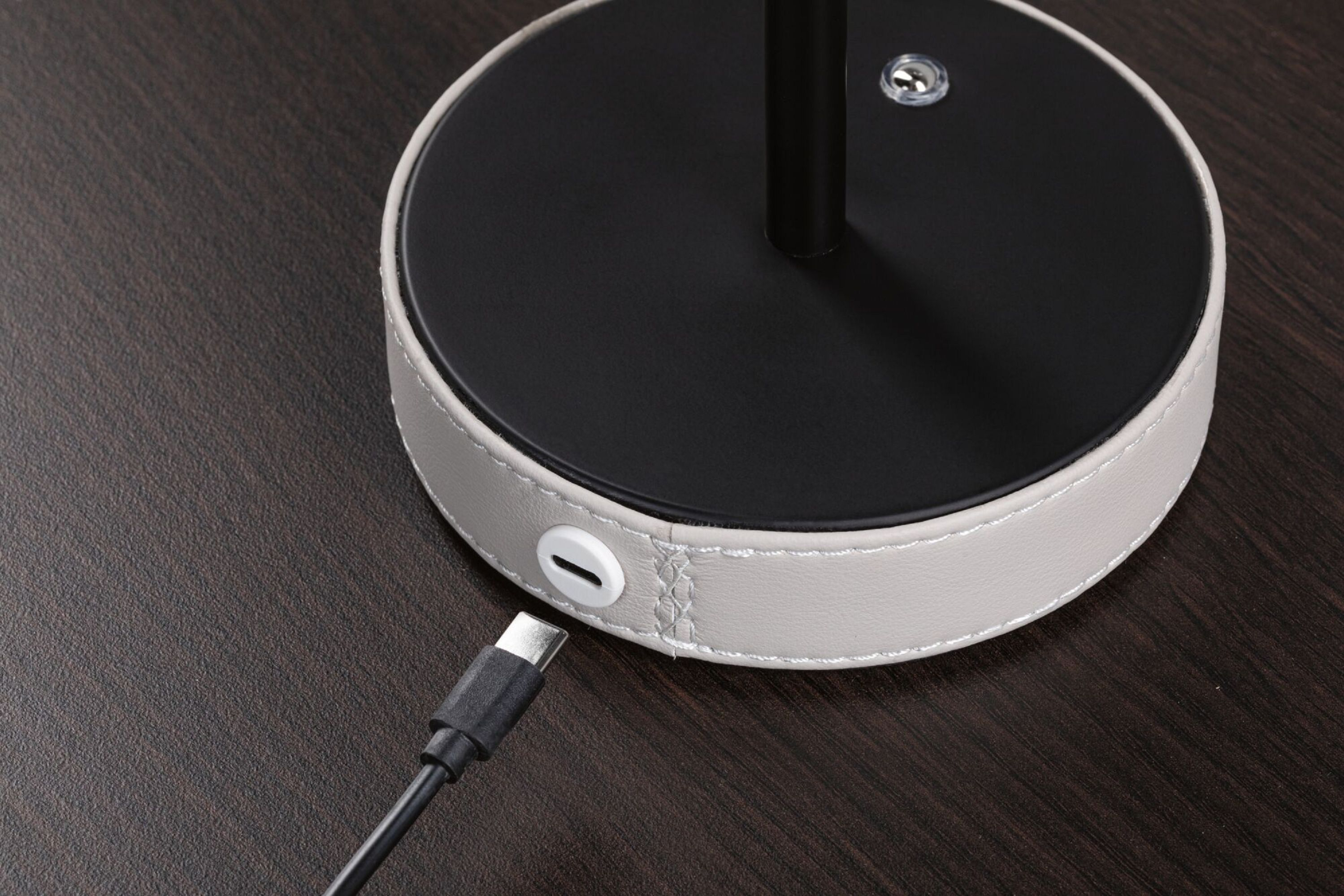 Zbliżenie na czarną podstawę lampy z szarym pierścieniem przypominającym skórę i portem ładowania USB-C.