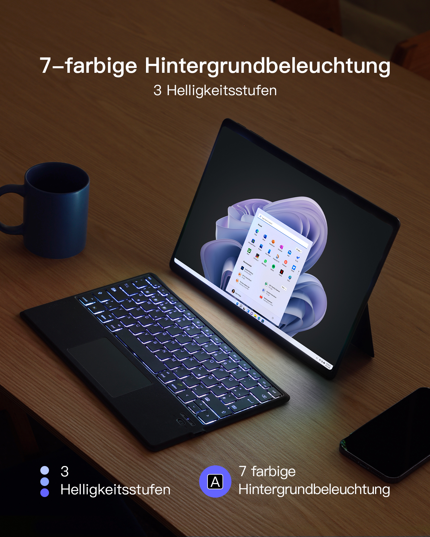 Ein Tablet und eine Tastatur mit leuchtender Tastatur, eine Tasse und ein Telefon auf einem Holztisch.