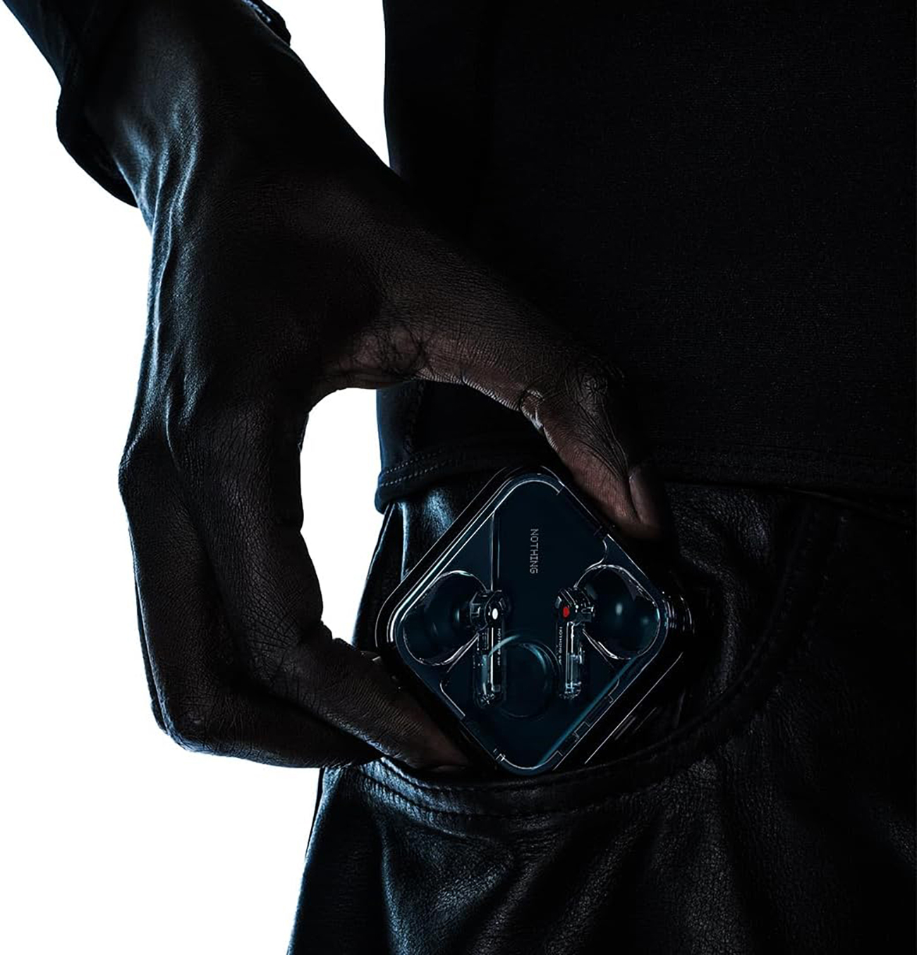 Dłoń trzyma przezroczyste etui na słuchawki z włożonymi słuchawkami w kieszeni. Marka Nothing.