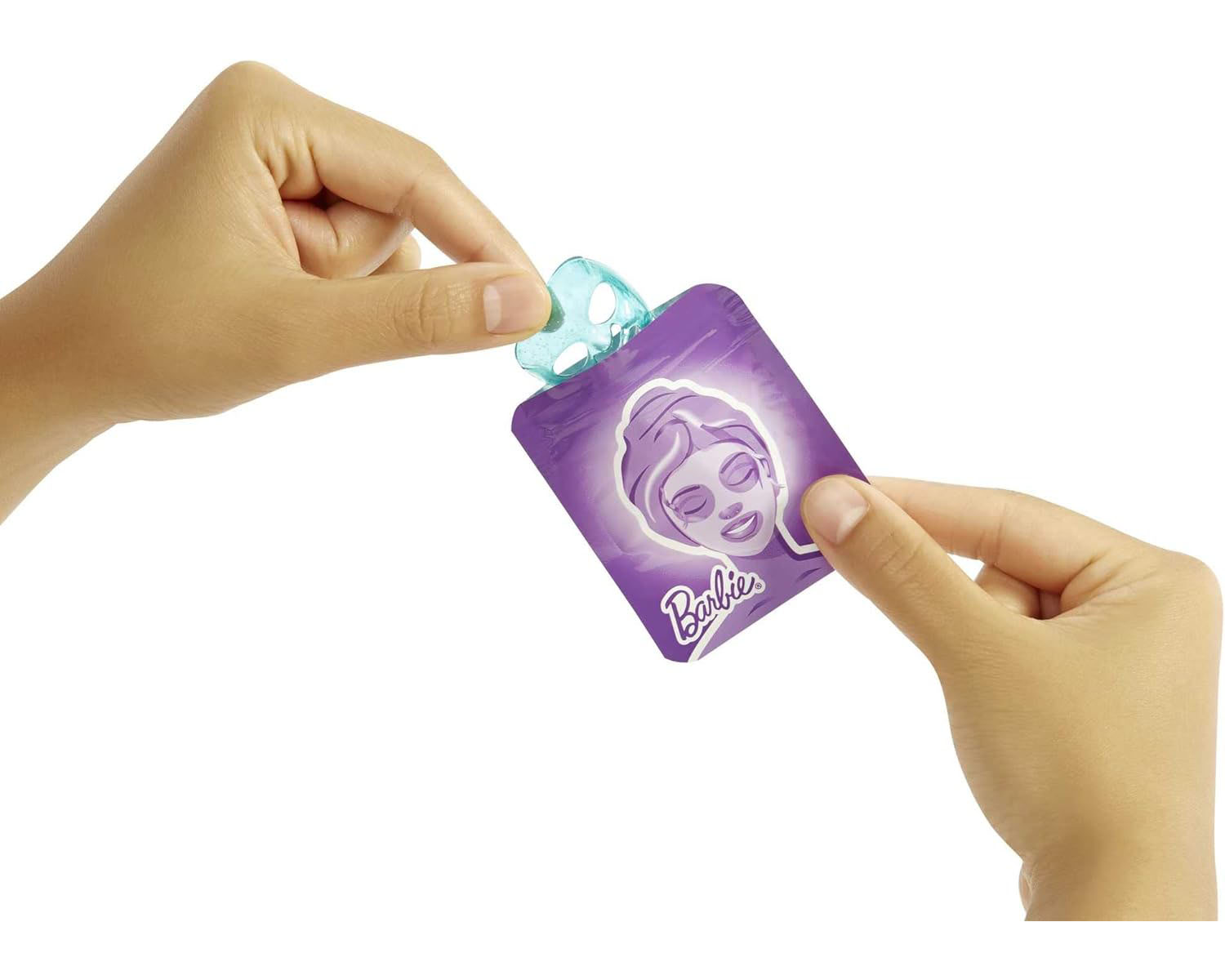 Mani che tengono un pacchetto di maschera per il viso Barbie. Il pacchetto è viola con un'illustrazione del viso di Barbie.