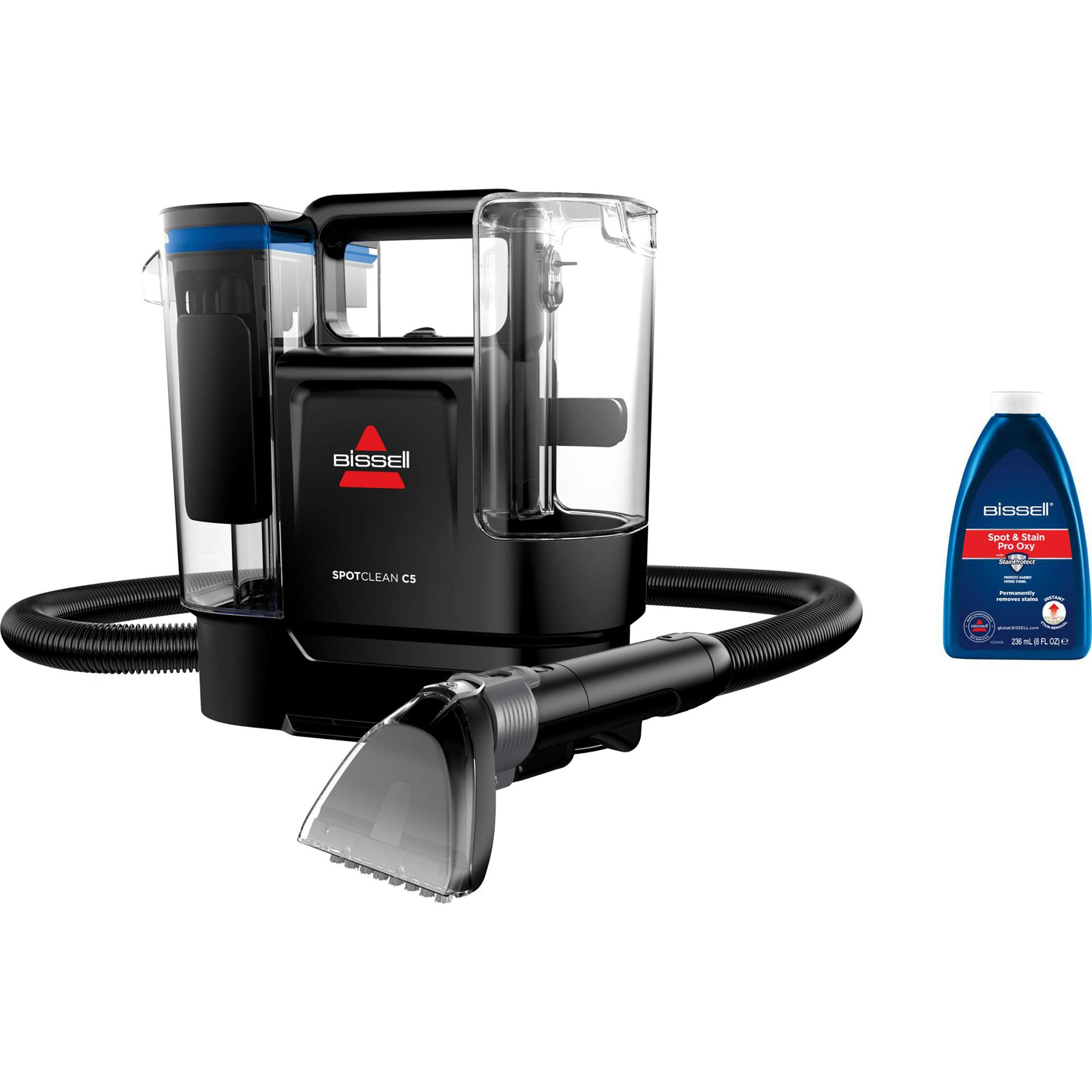 Schwarzer Bissell SpotClean C5 Teppichreiniger mit einer Flasche Lösung, weißer Hintergrund.
