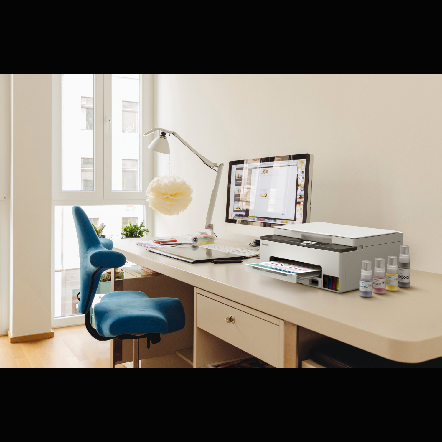 Nowoczesne biuro z komputerem, drukarką i niebieskim krzesłem. Pokój ma naturalne światło.