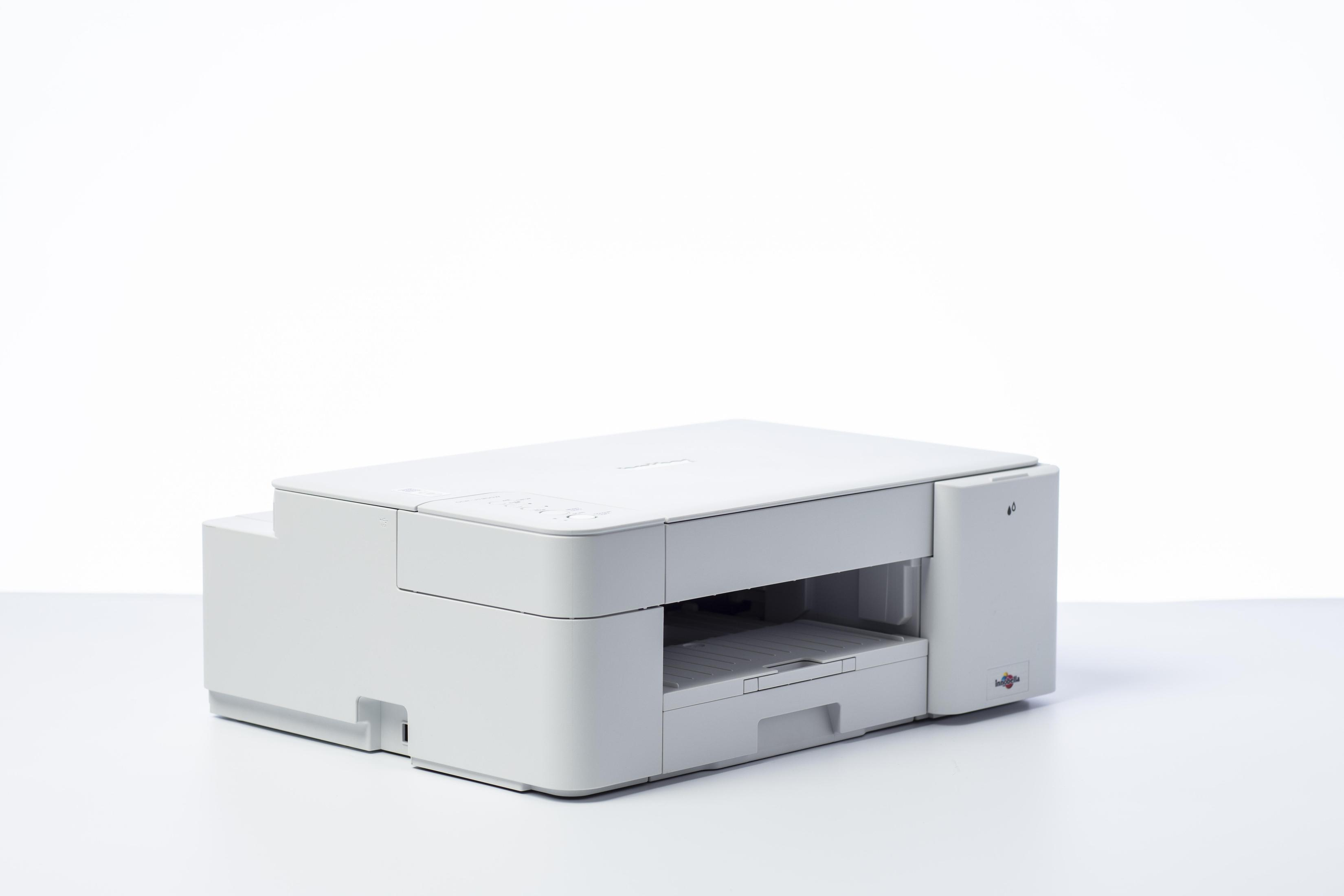 Biała drukarka na białej powierzchni z wysuniętą szufladą na papier.