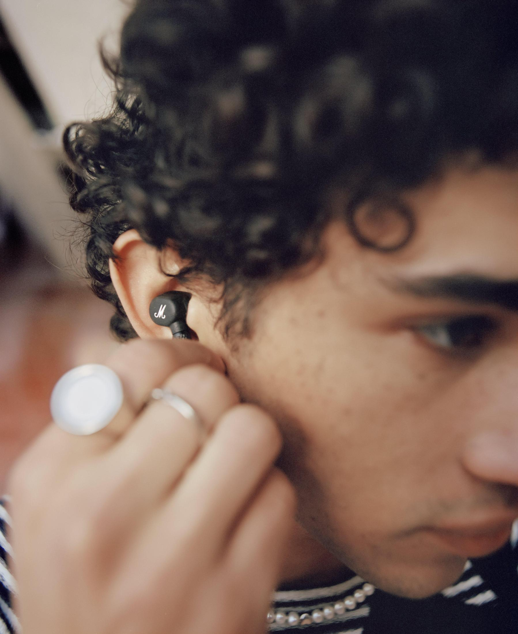 Uomo con un auricolare nero nell'orecchio, con un anello al dito.