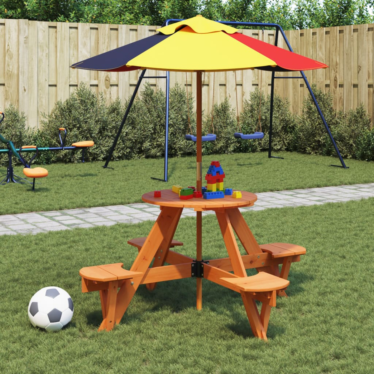 Ein Holztisch mit buntem Sonnenschirm, Spielzeug und Fußball in einem grasbewachsenen Garten.