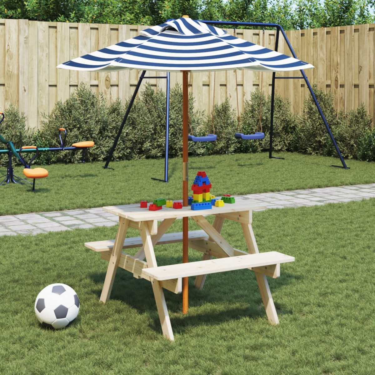 Ein Picknicktisch mit Sonnenschirm, Blöcken und einem Fußball in einem grasbewachsenen Garten.
