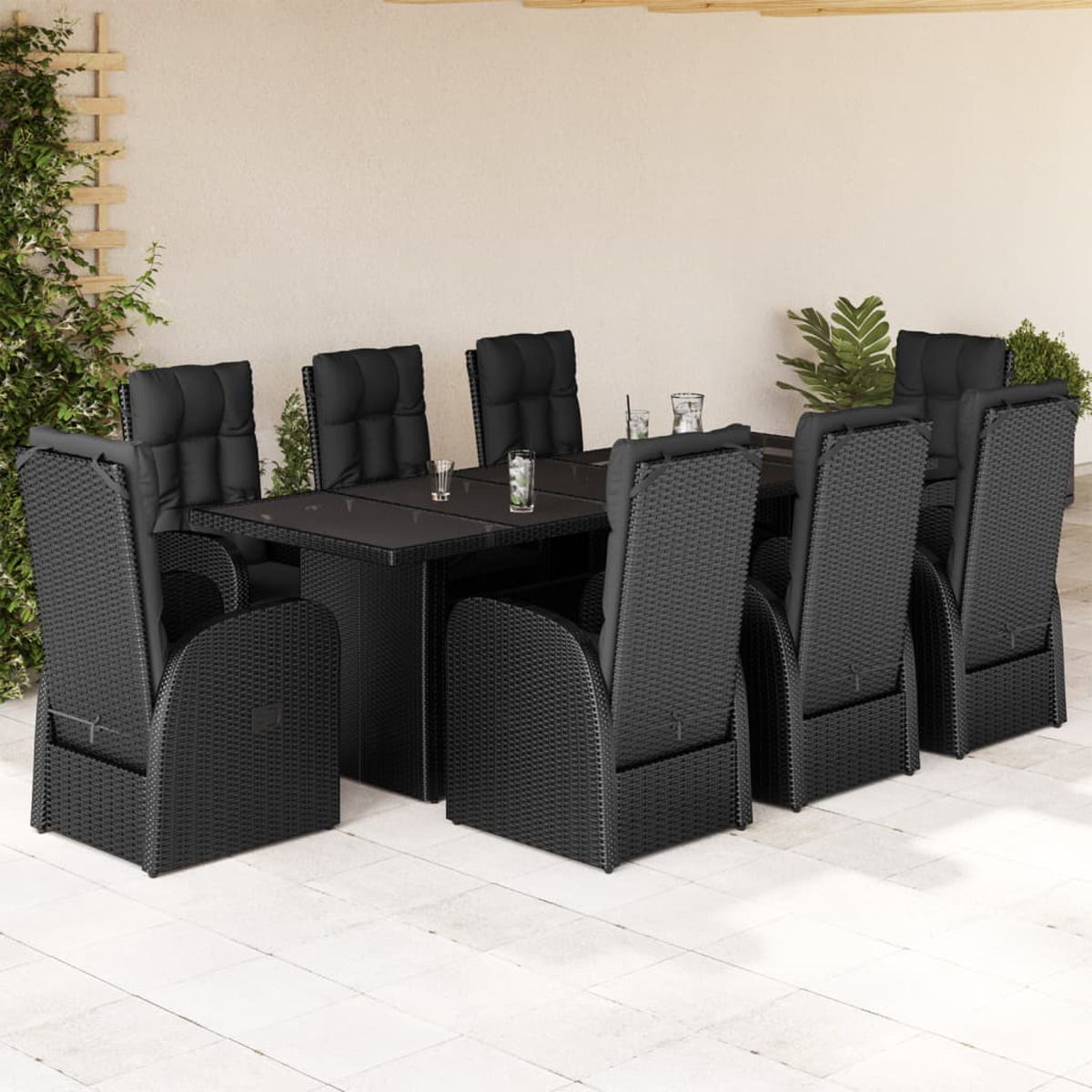Set da pranzo all'aperto con un tavolo in vetro nero e sedie in vimini nero con cuscini. L'ambientazione è all'aperto.