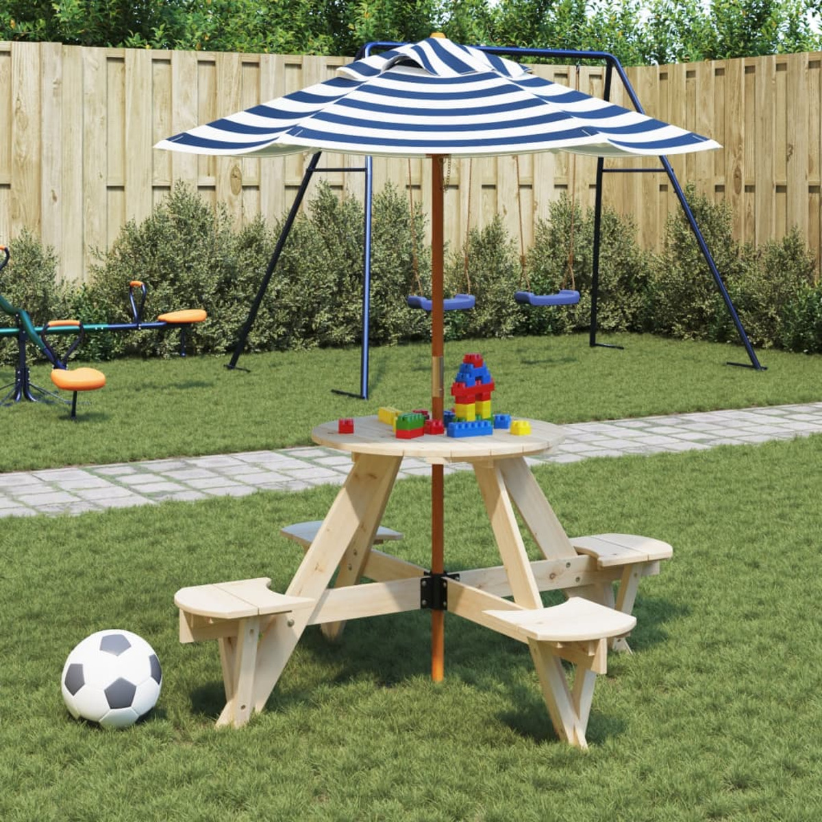 Picknicktisch mit Spielzeug, Fußball und gestreiftem Schirm in einer grasbewachsenen Szene.