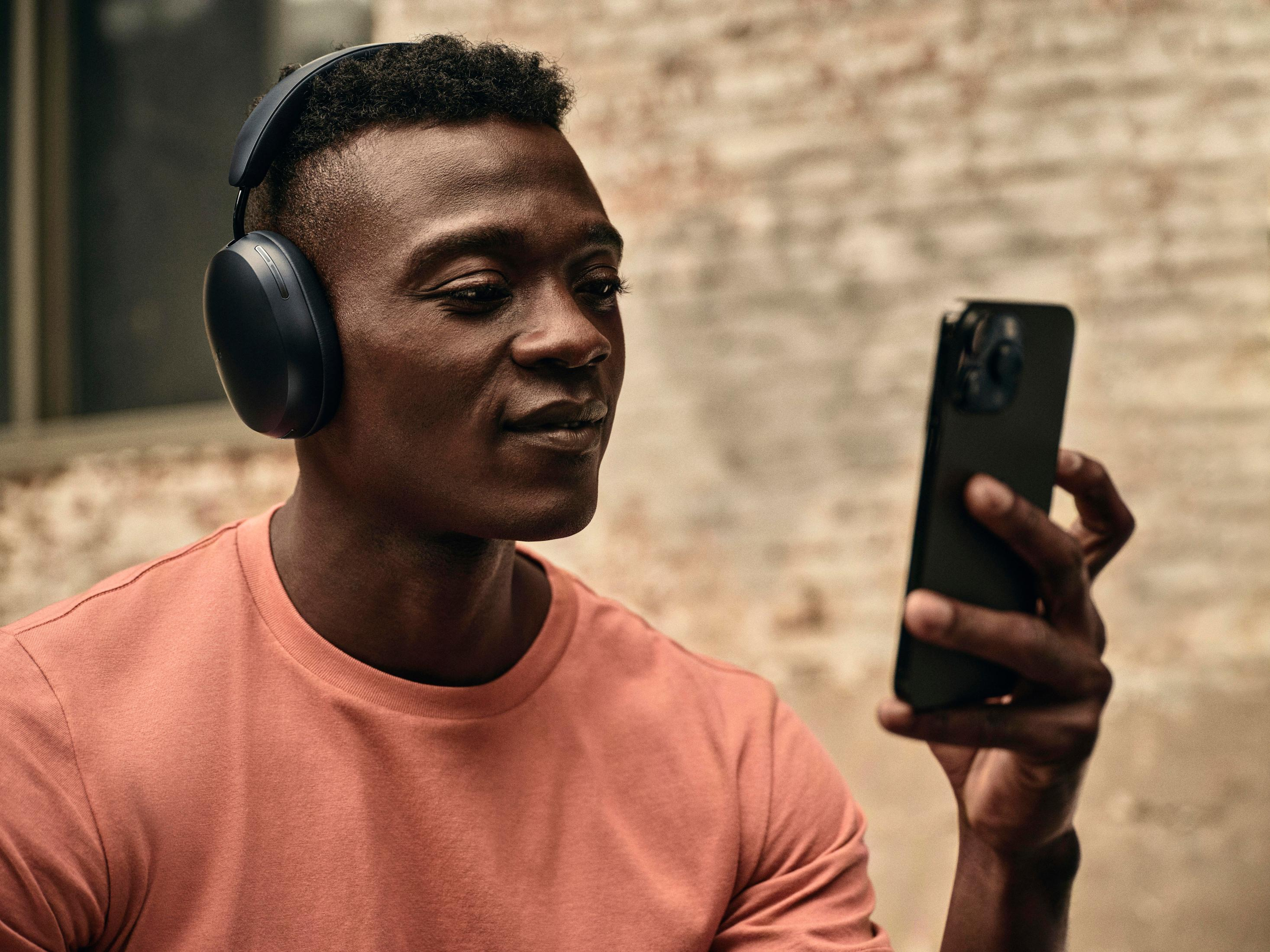 Mężczyzna w słuchawkach trzymający czarny smartfon.