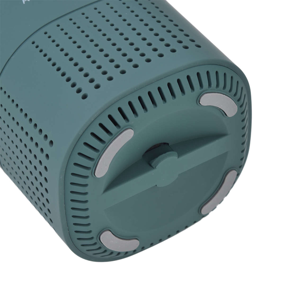 Ein teal-farbenes Gerät mit perforierter Oberseite, einem Sockel mit grauen Pads und einem zentralen Knopf.