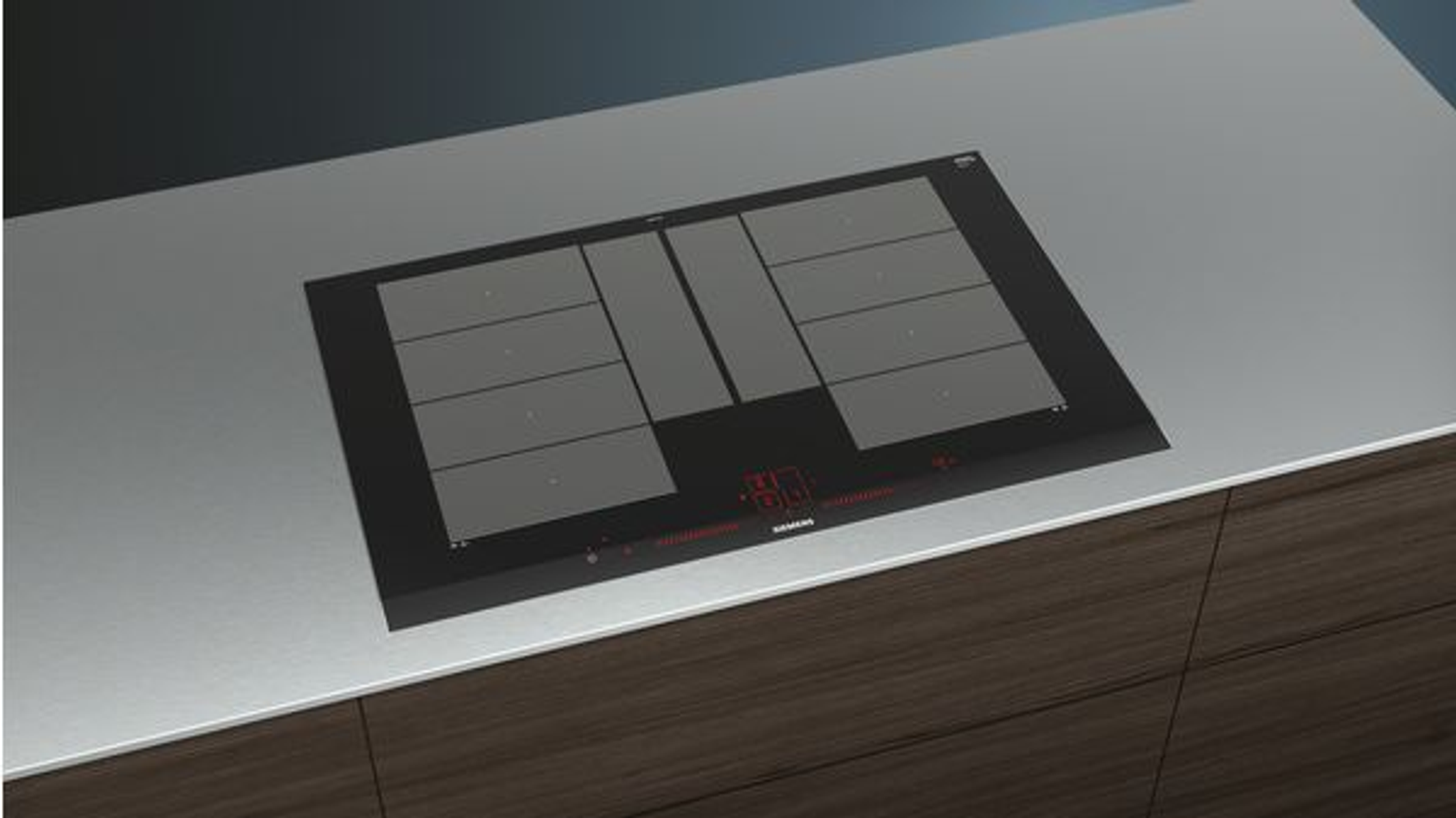 Piano cottura a induzione nero con display rosso su un piano di lavoro grigio e un mobile in legno.