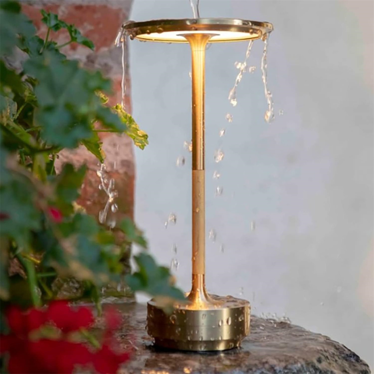 Eine goldfarbene Tischlampe mit Wasser, das von oben fließt, auf einer Steinoberfläche.