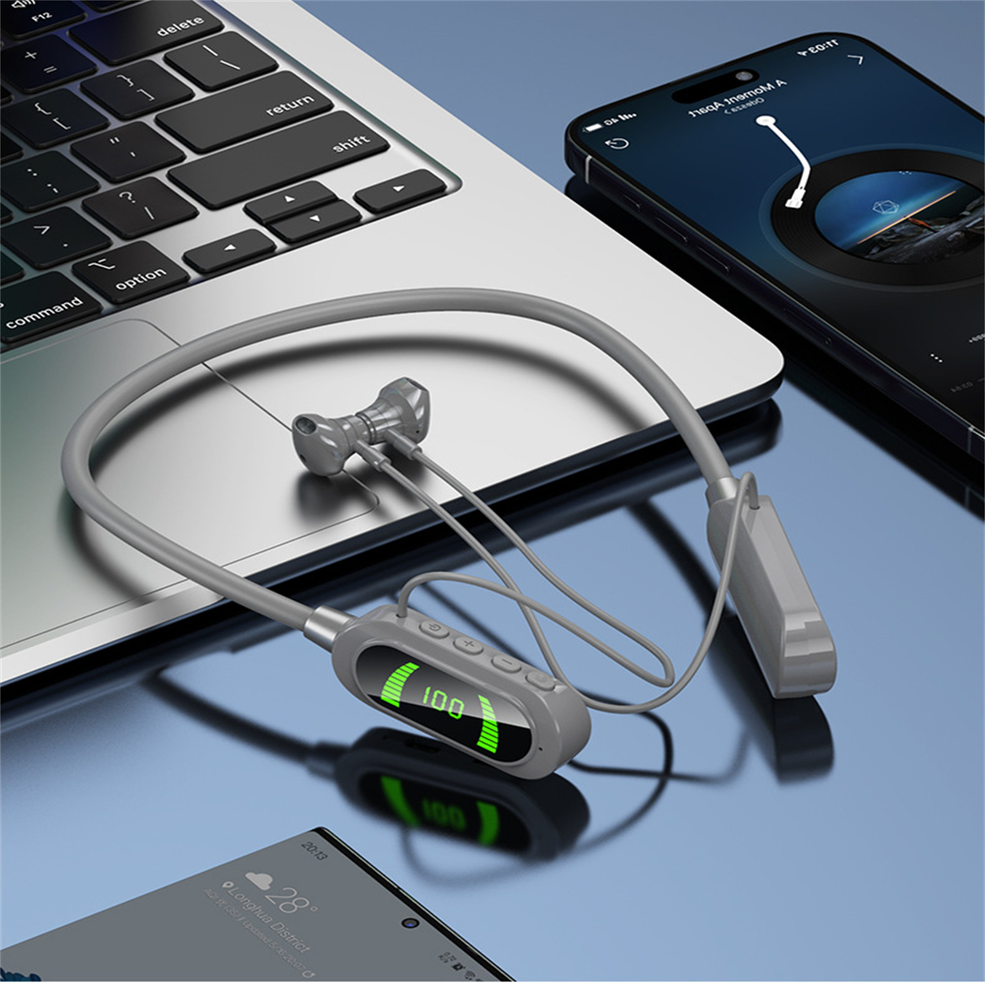 Graue Bluetooth-Kopfhörer auf einem Laptop. Smartphone und Tablet im Hintergrund.