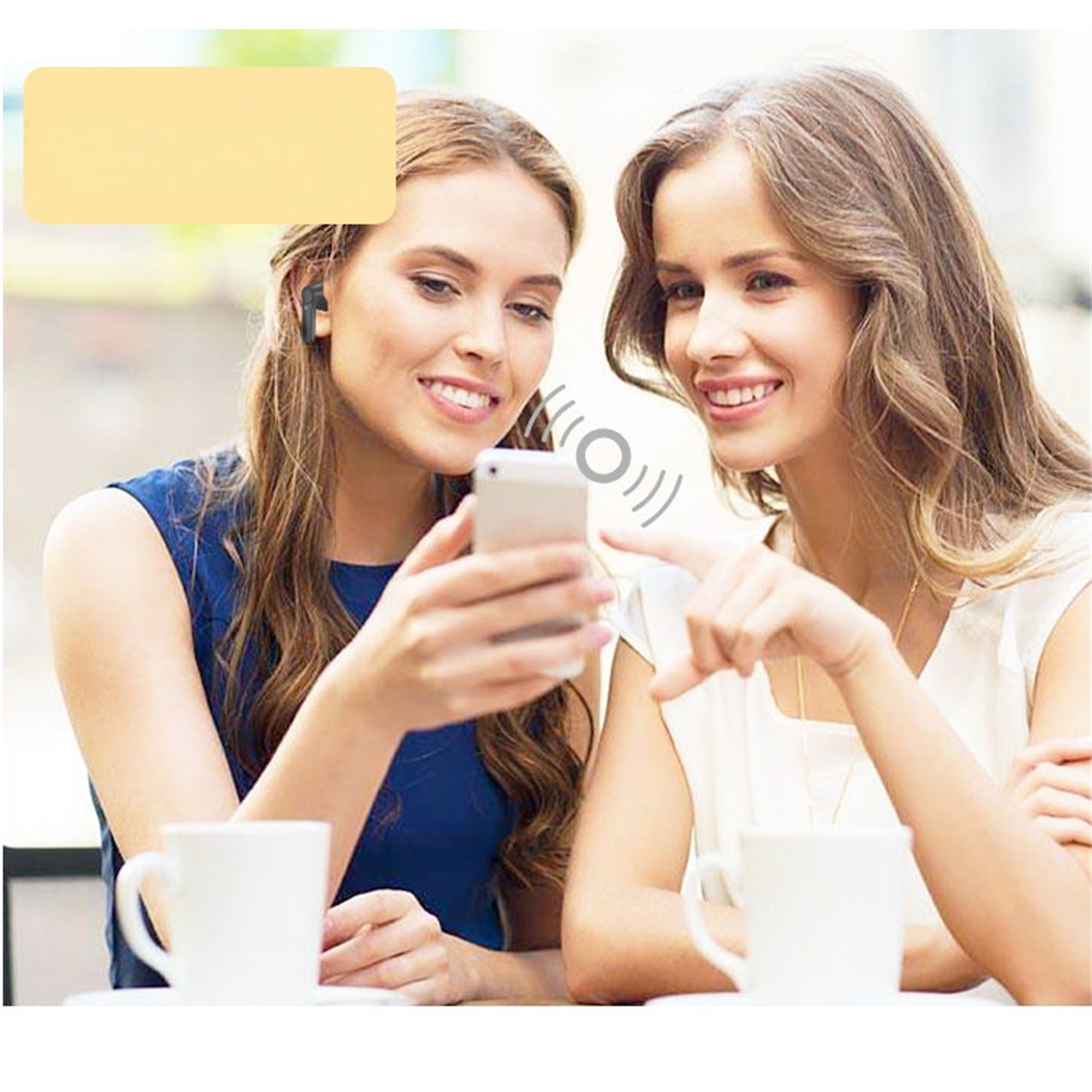 Zwei Frauen schauen auf ein Telefon, eine trägt einen kabellosen Ohrhörer und die andere zeigt darauf.