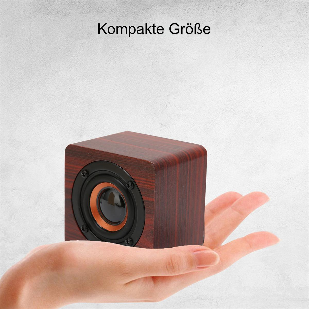 Kleiner, hölzerner Lautsprecher, der von einer Hand gehalten wird. Braune Farbe. Runde Lautsprecherelement.