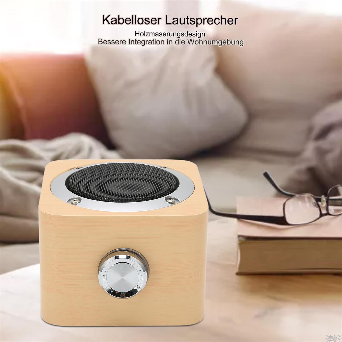 Ein Lautsprecher aus Holz mit Metallgitterfront, silbernem Knopf und einem Buch.