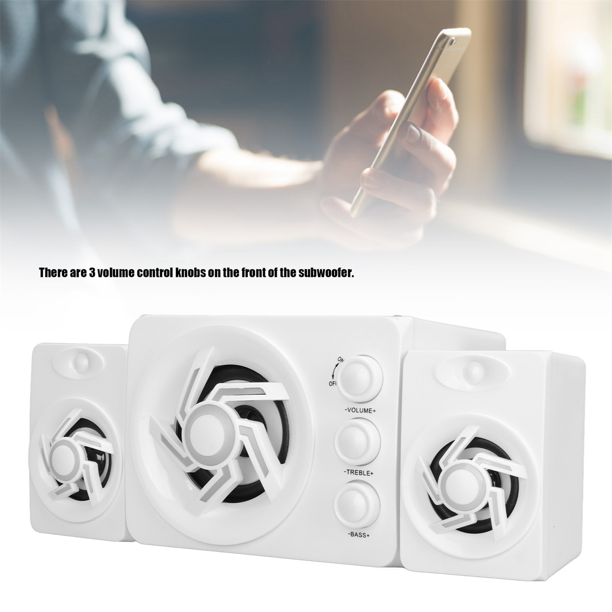 Weißer Subwoofer mit drei Lautstärkereglern, Person hält Telefon.