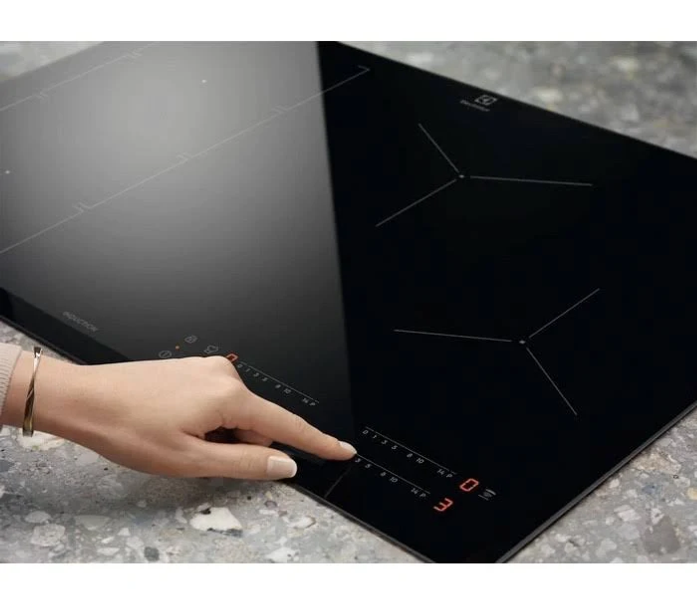 Dłoń kobiety dotykająca cyfrowego panelu sterowania czarnej płyty indukcyjnej.