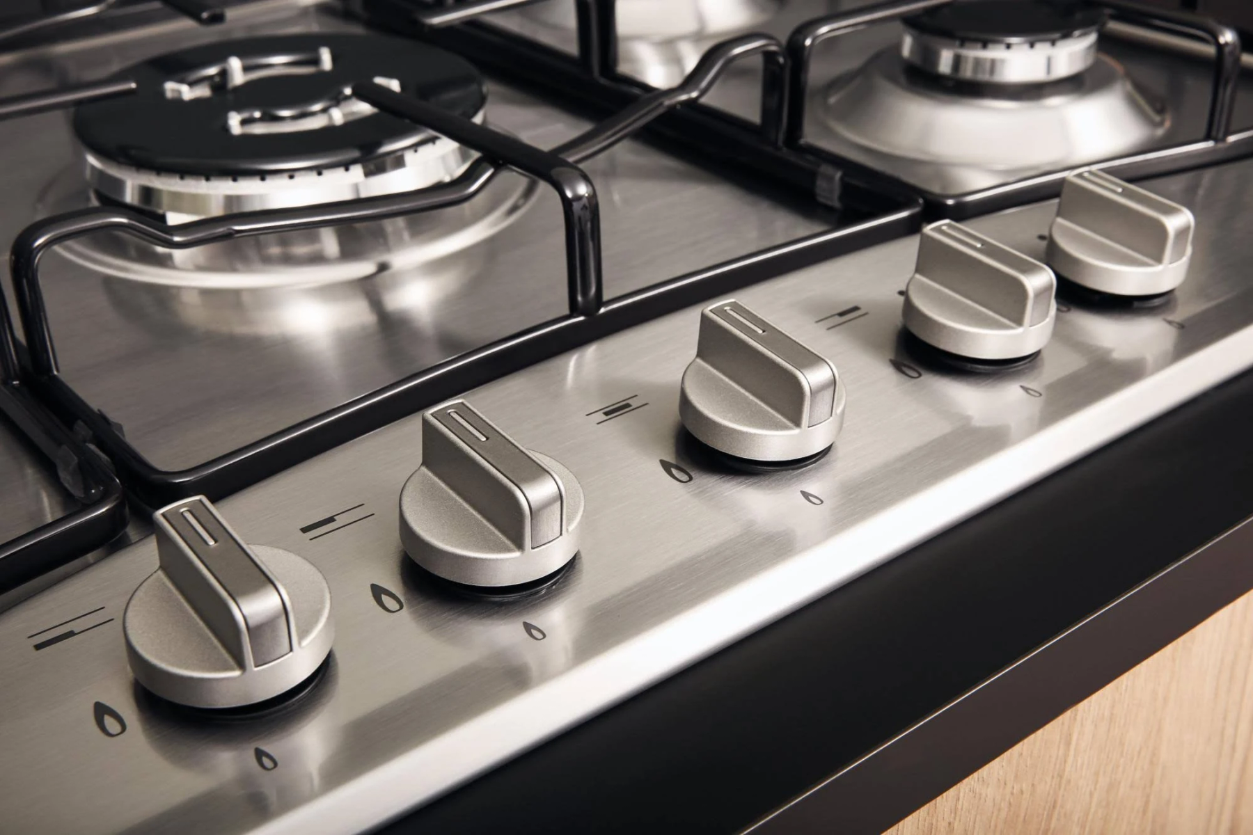 Zbliżenie płyty gazowej ze stali nierdzewnej z pokrętłami i palnikami.