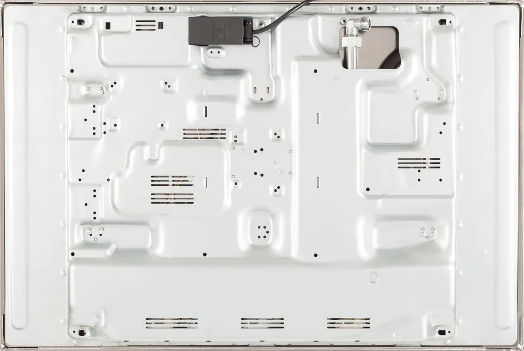 Spód dużego, srebrnego urządzenia z otworami wentylacyjnymi, śrubami i podłączeniem.