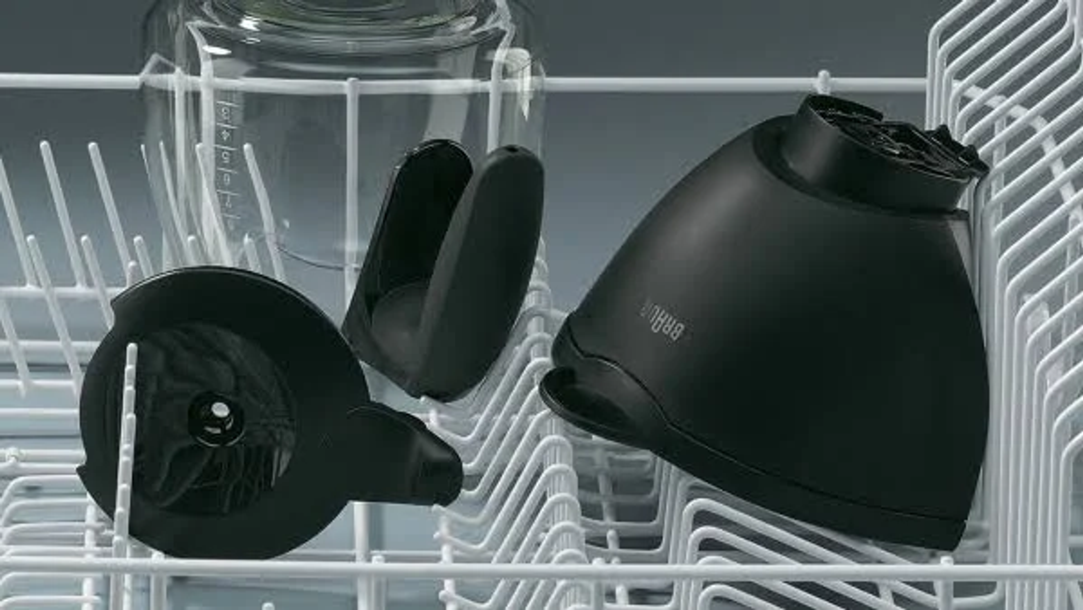 Vaatwasser met Braun onderdelen, zwarte hulpstukken en een transparante glazen container, in een rek.