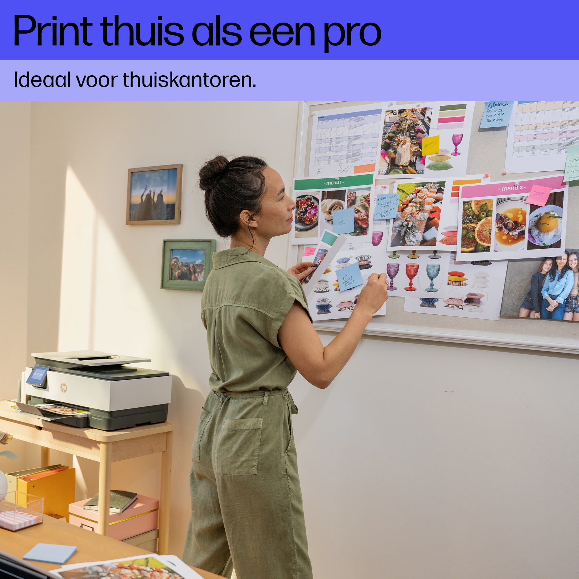 Een vrouw bij een printer, kijkt naar een whiteboard met foto's en notities. Thuis kantoor.