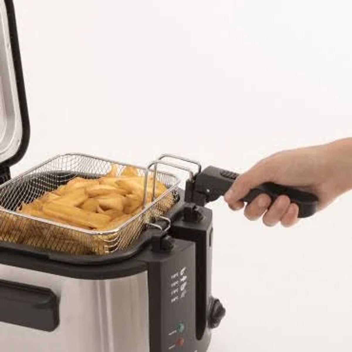 Freidora plateada con una cesta de patatas fritas. Una mano sostiene el asa de la freidora.