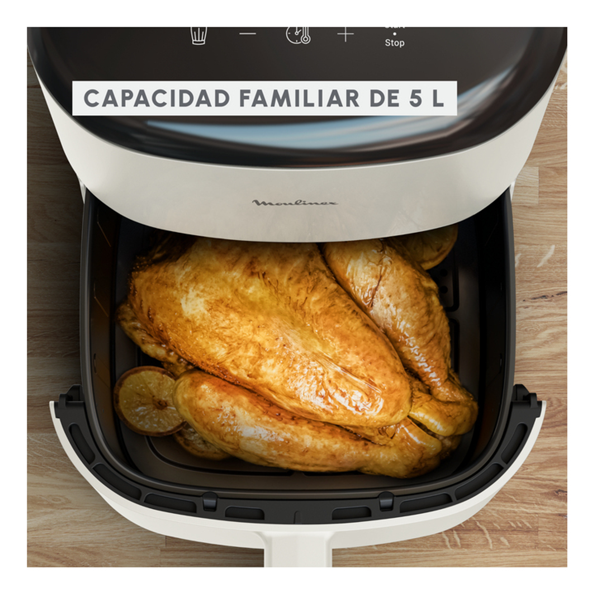 Una freidora de aire abierta con pollo cocido y limones dentro. Tapa blanca e interior negro.
