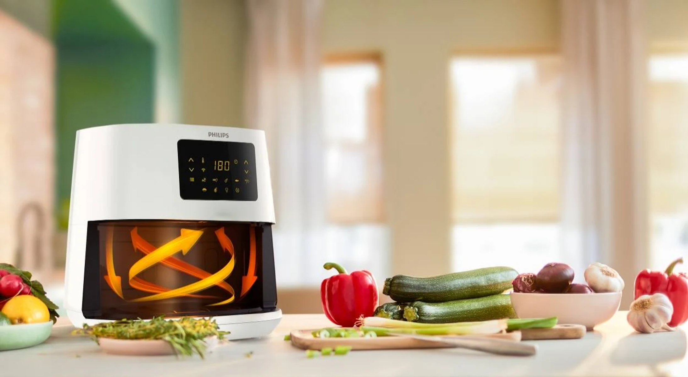 Frytkownica powietrzna z warzywami na stole. Strzałki wewnątrz pokazują cyrkulację powietrza.