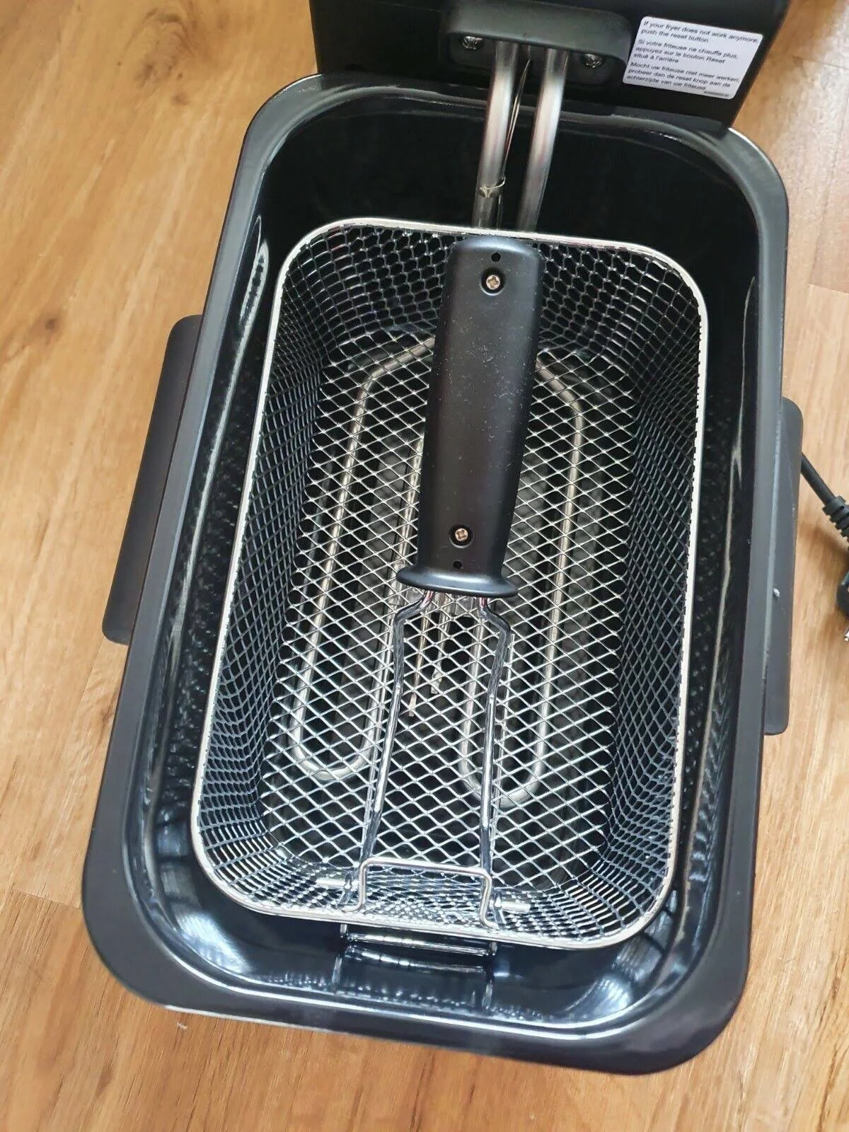Una freidora abierta con una cesta de malla en el interior, vista desde arriba.