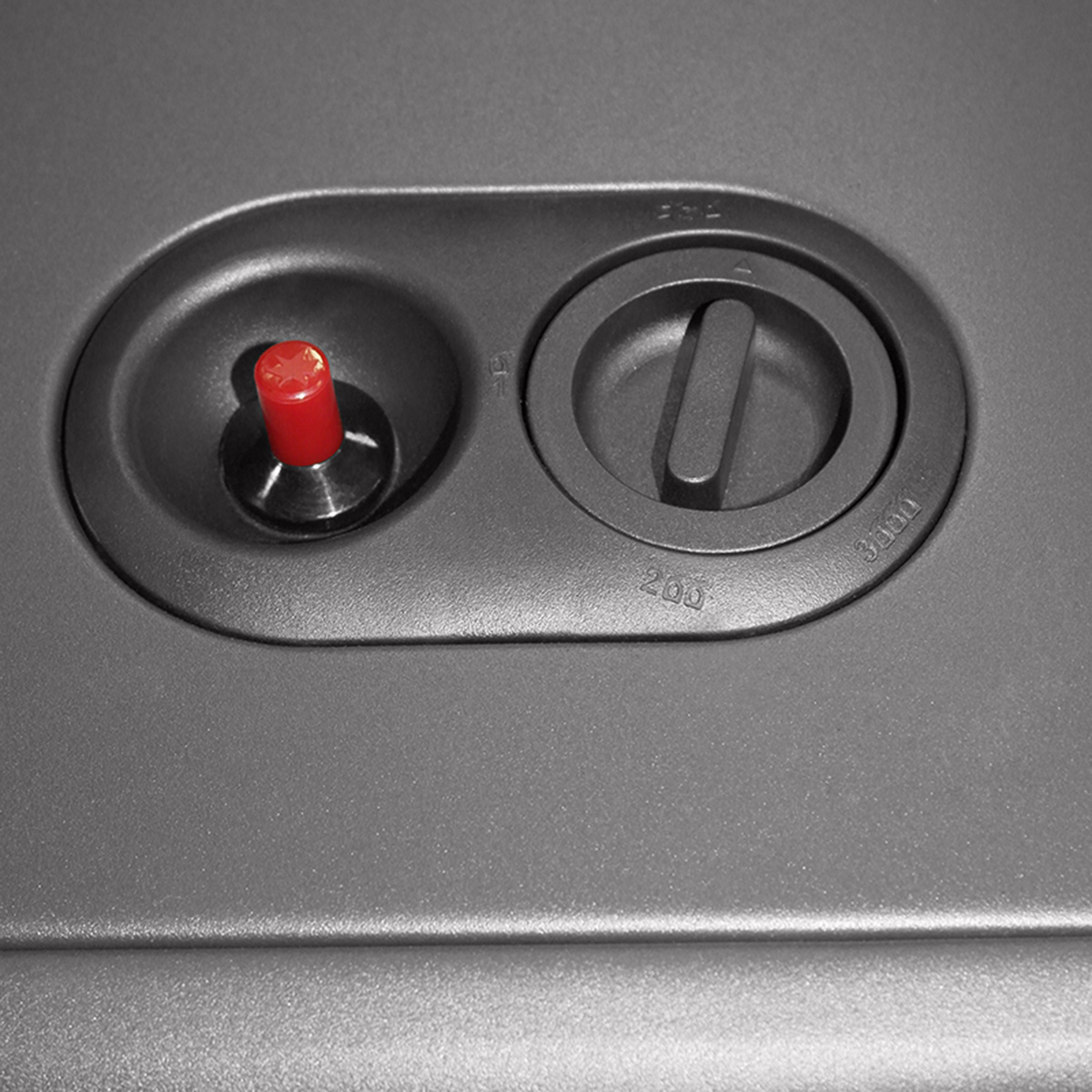 Primer plano de un panel de control gris con un botón rojo y un dial.