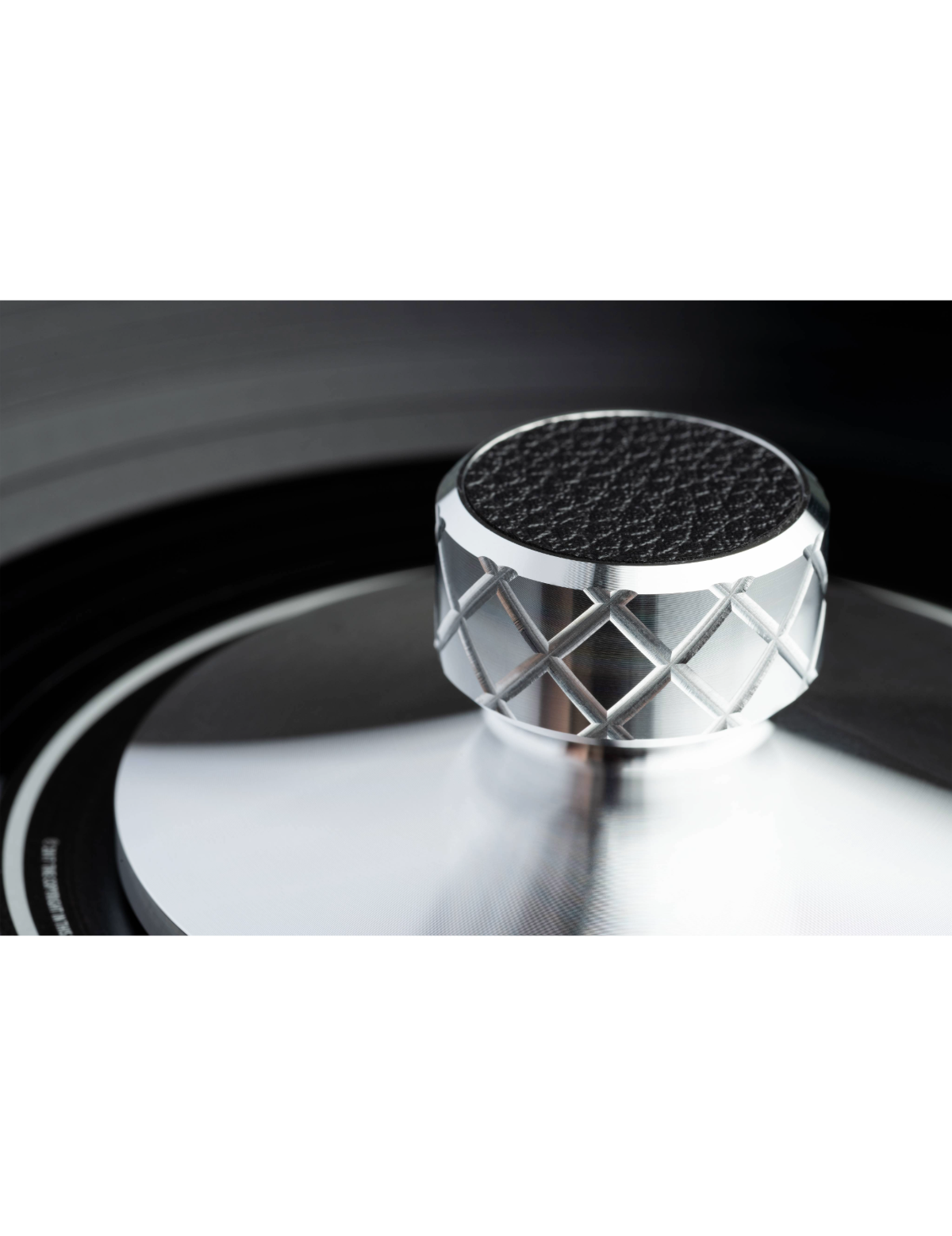Close-up of a silver and black record weight on a turntable.