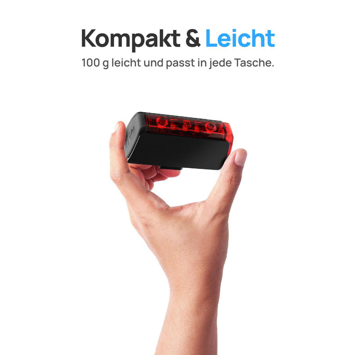 Ein kleines, schwarzes rechteckiges Gerät mit roten Lichtern wird von einer Hand vor weißem Hintergrund gehalten.