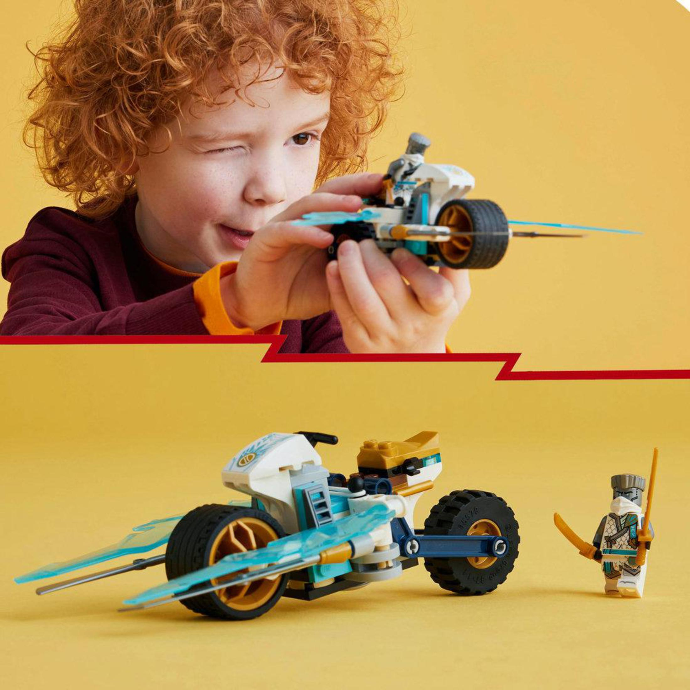 Ein Junge zwinkert und hält ein Lego Ninjago Motorrad-Spielzeug. Eine Lego Ninja-Figur steht daneben.