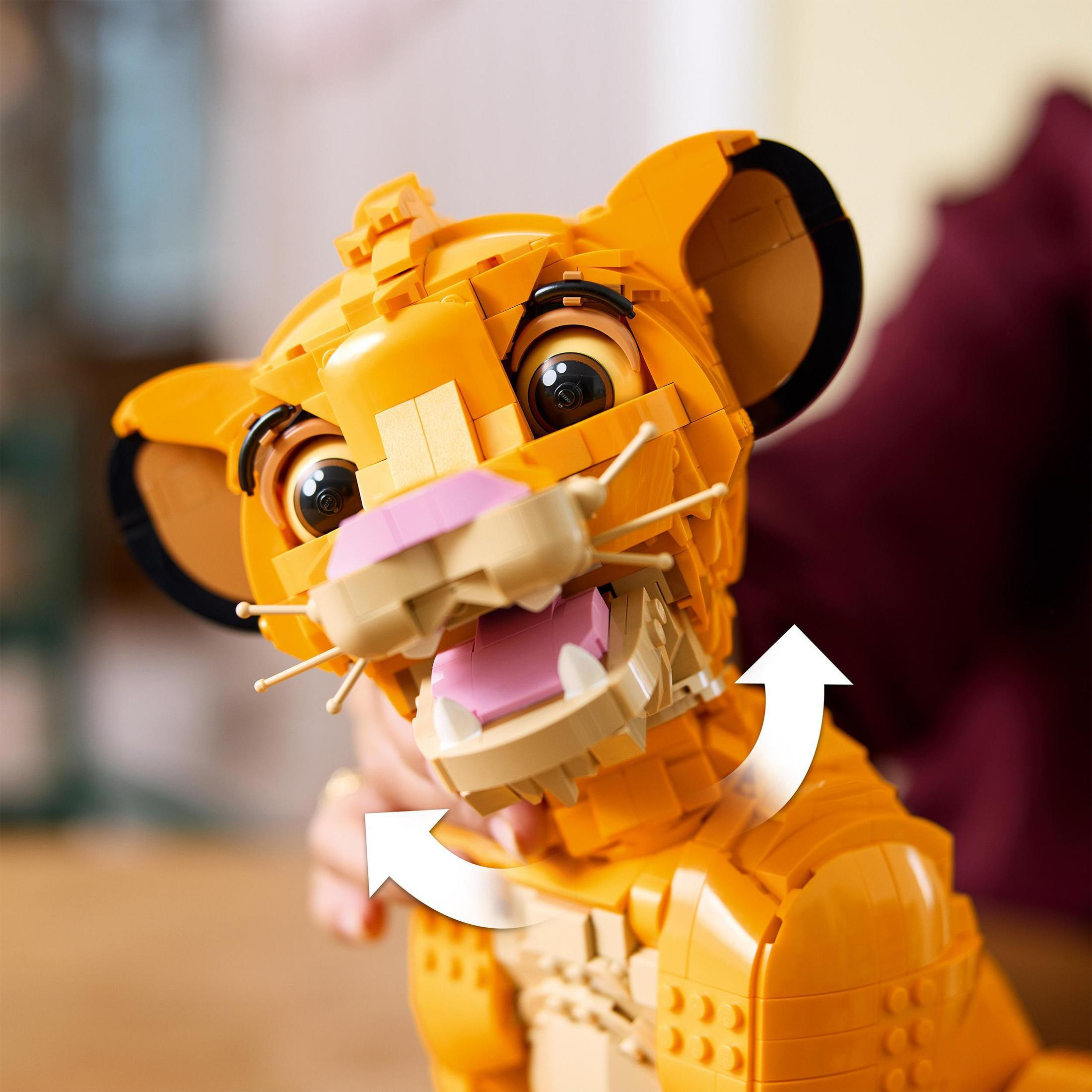 Zabawka Lego Simba z otwartą buzią, zębami i różowym językiem, ze strzałkami.