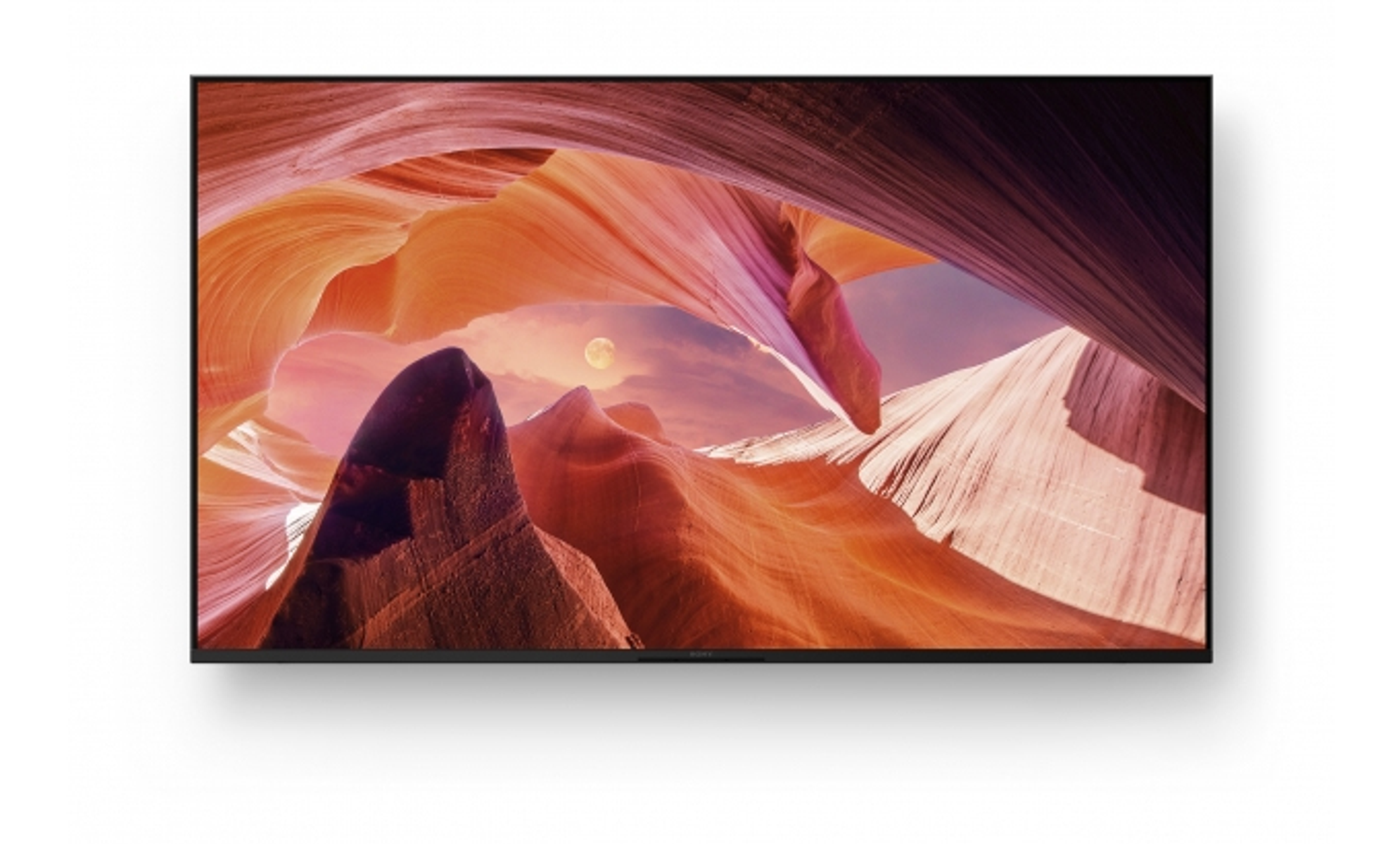 Un televisore widescreen che mostra una vista panoramica di un canyon con la luna piena.